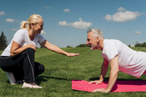 Um casal de idade realizando exercícios físicos ao ar livre.