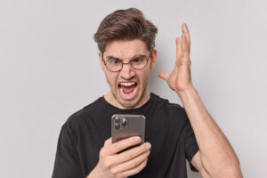 Homem com o celular na mão estressado